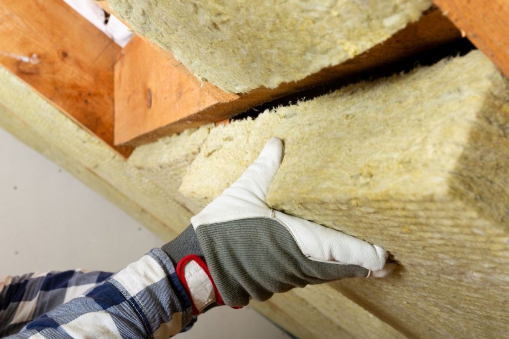 A person in gloves holds a piece of insulation, representing an insulation service in action.