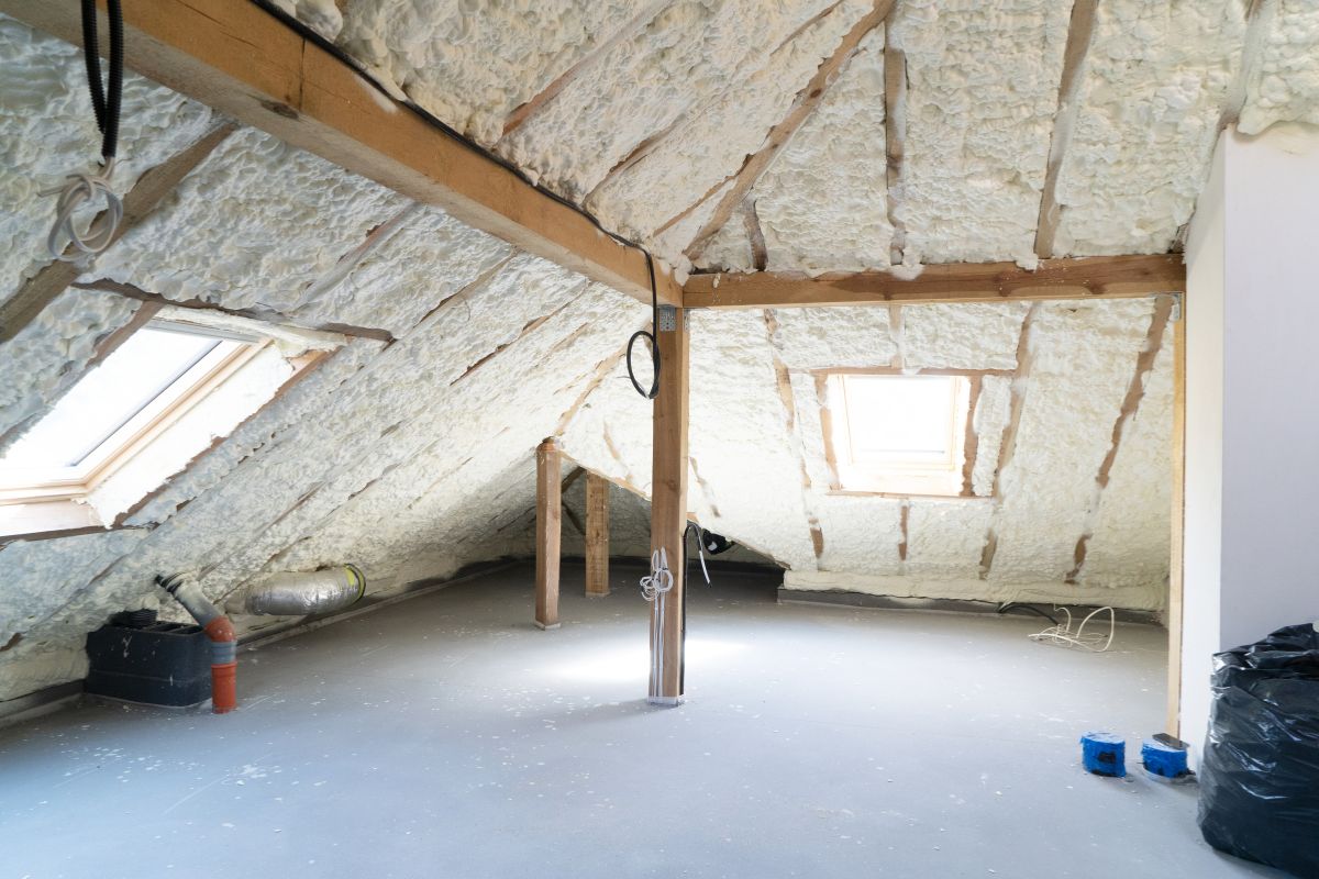 An attic featuring insulation materials and a wooden ladder, highlighting a space prepared for insulation service.